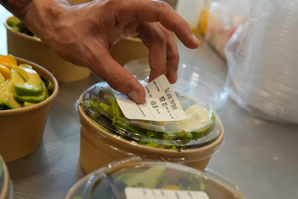 Application d’une étiquette Traceo sur une salade préparée.