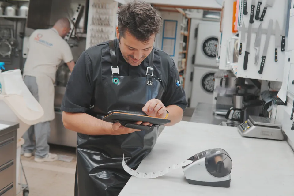 Professionnel utilisant une tablette Traceo dans une cuisine en activité.