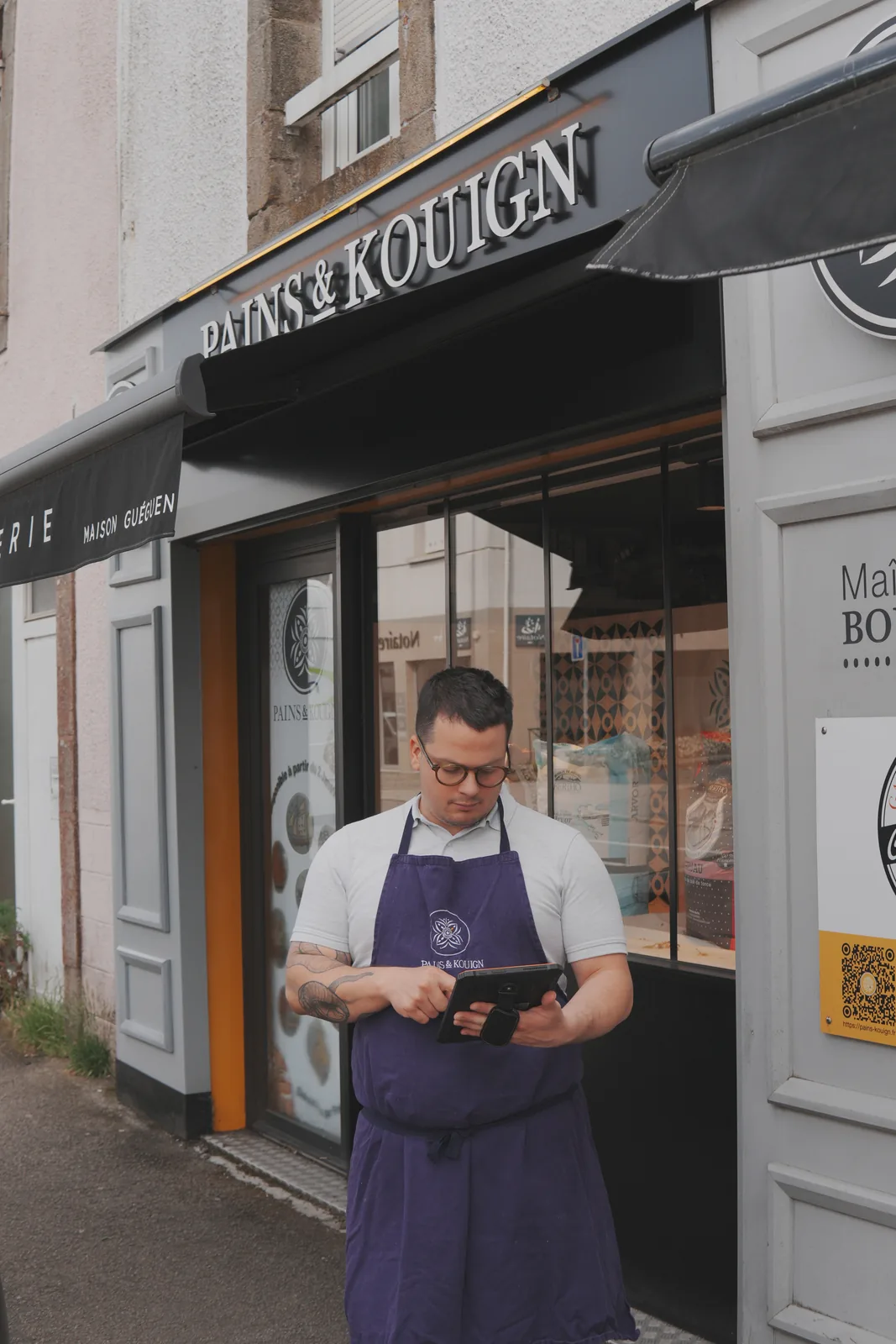 Professionnel tenant une tablette Traceo devant la boulangerie Pains et Kouign.